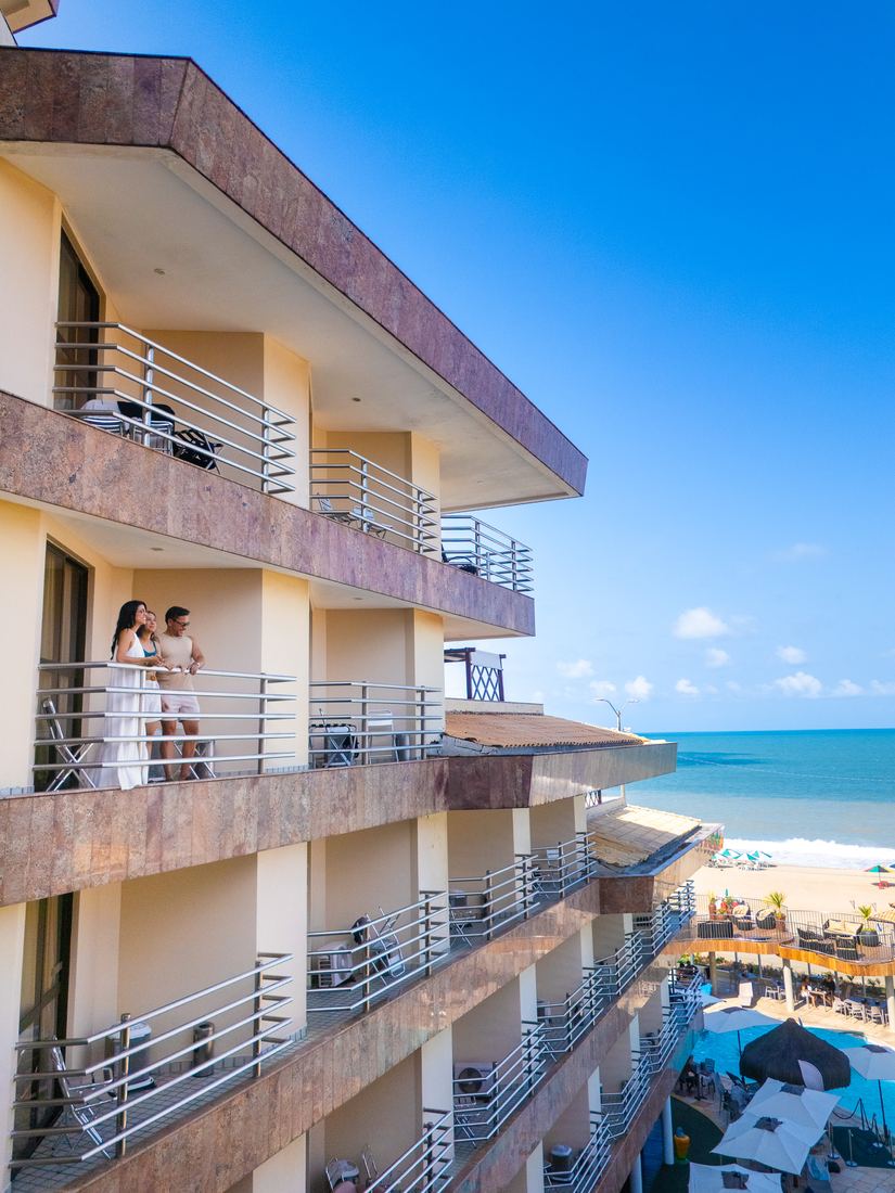 Casal na varanda do apartamento com vista pro mar